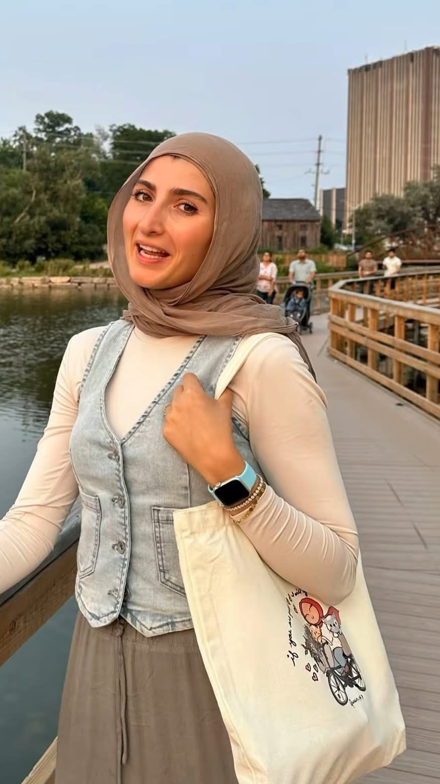 Lujain walking outdoors along a waterside boardwalk