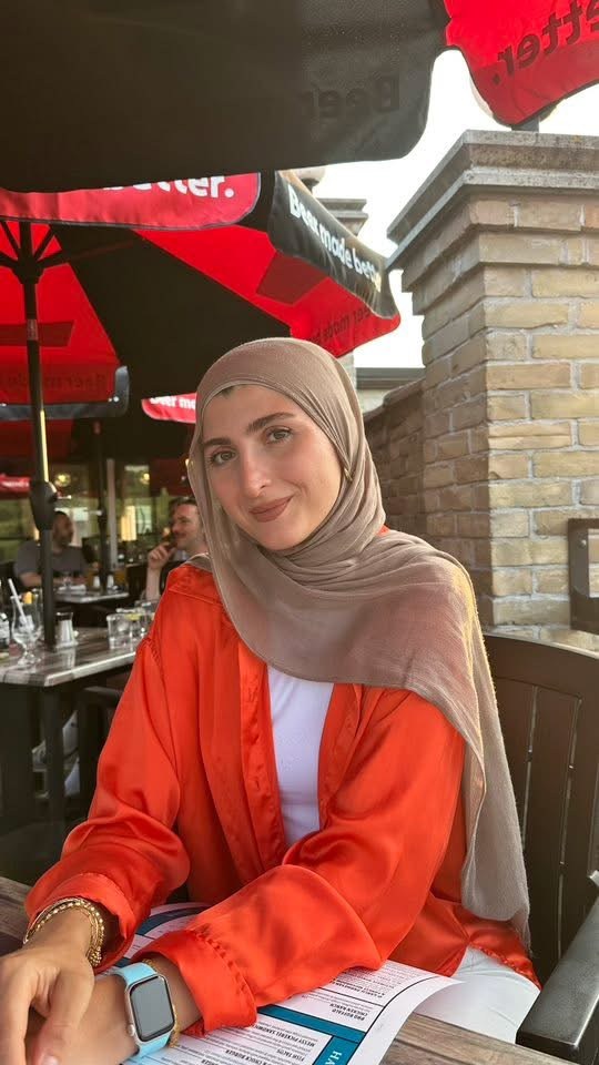 Lujain seated at an outdoor restaurant patio table